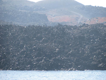 Black rocks of the Santorini volcano The black rocks of the volcano in Nea Kameni, falling to the Aegean sea
