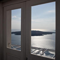 Blue sea and Santorini volcano from inside a balcony door.