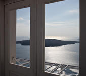 Blue sea and Santorini volcano from inside a balcony door.